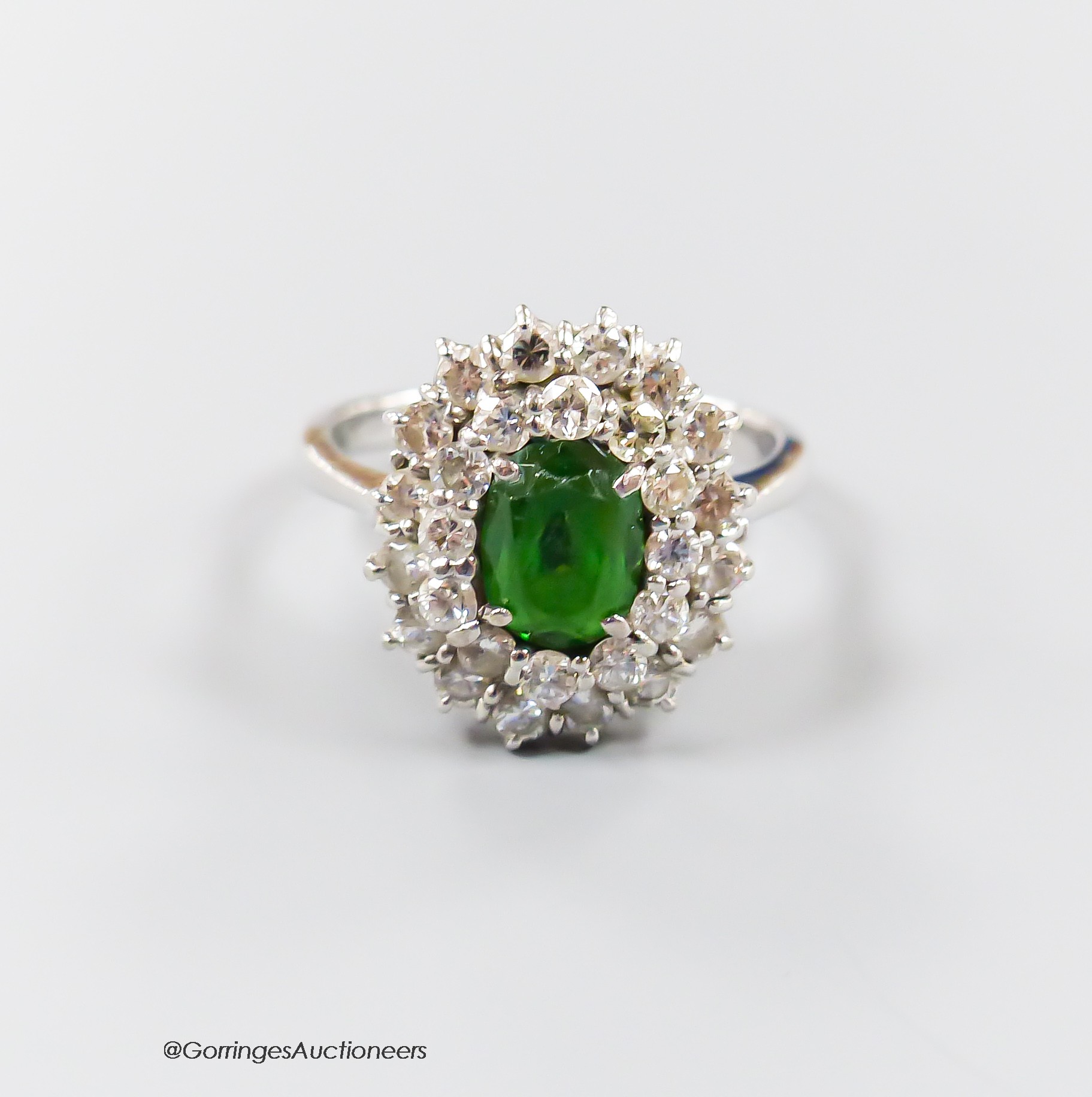 A modern 18ct white gold, green garnet and diamond set oval cluster ring, size N, gross weight 5.3 grams.